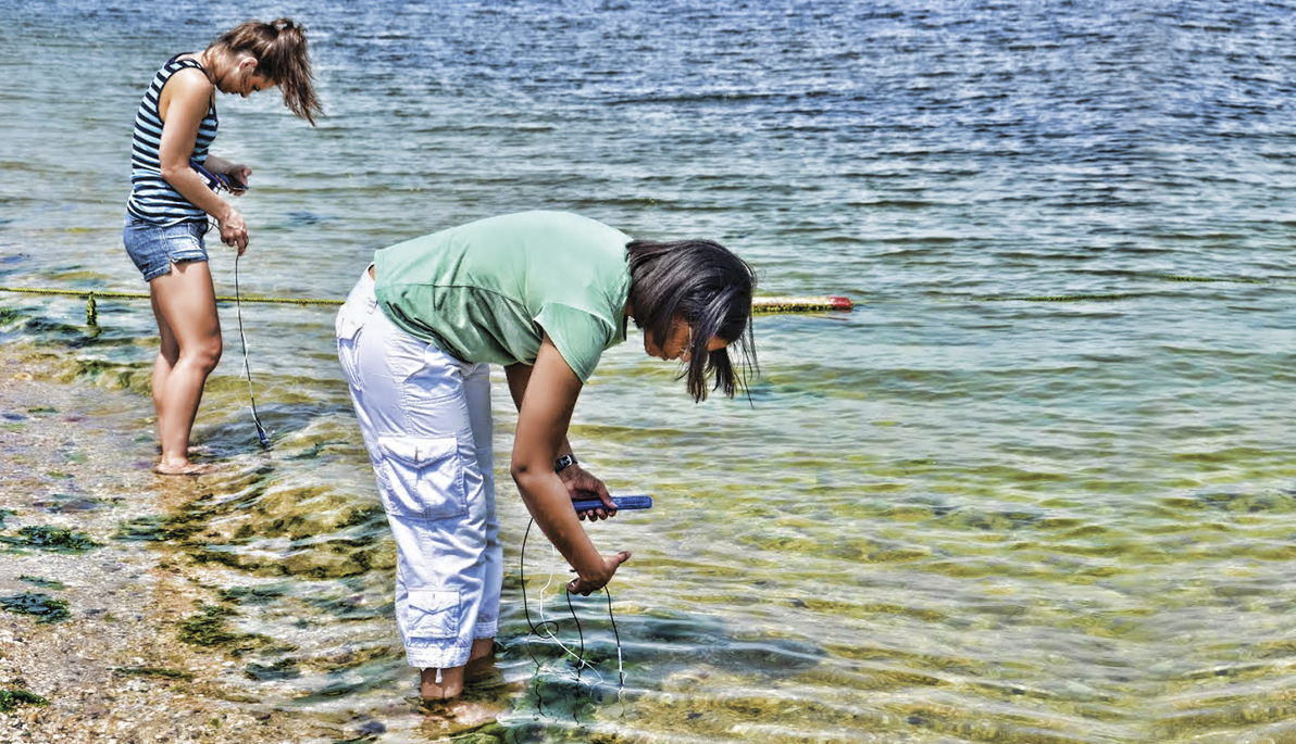Women testing water on a beach.