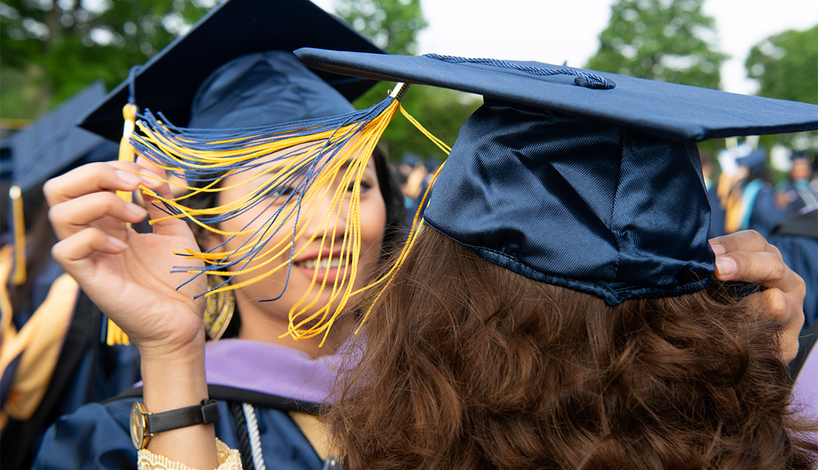 Close-up of two graduates in mortarboards and tassels facing each other