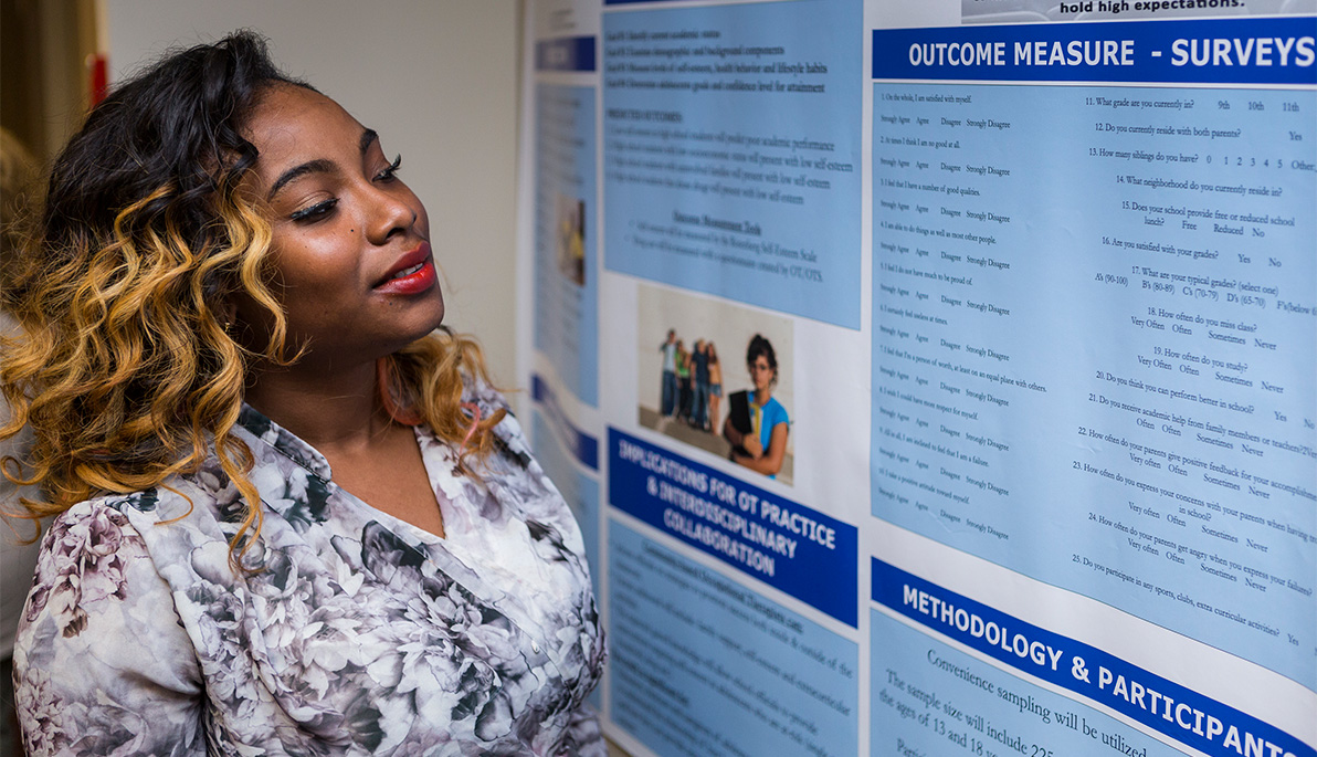 Student reads poster presentation from Aletheia Conference