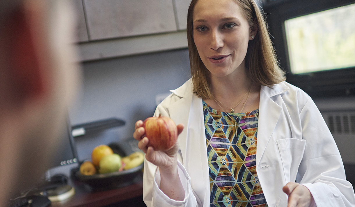 Professor in lab coat holding an apple