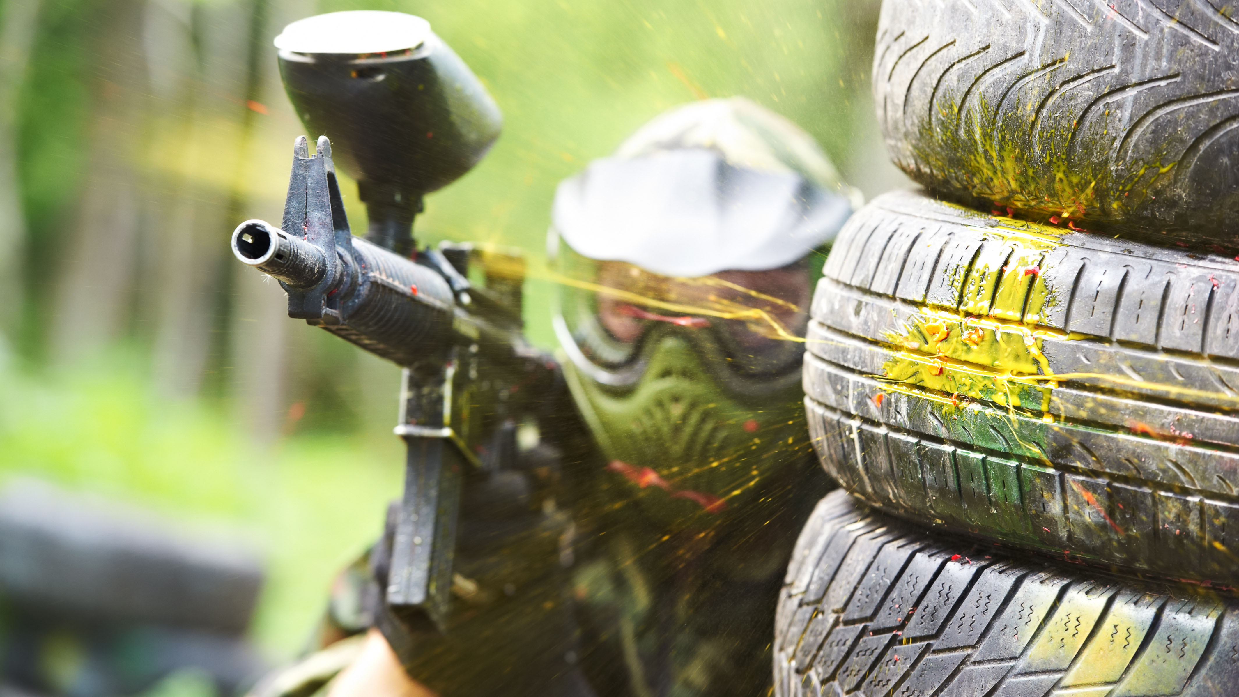 Paintballer crouching behind tire