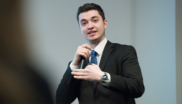 Student in a suit and tie speaking into a microphone