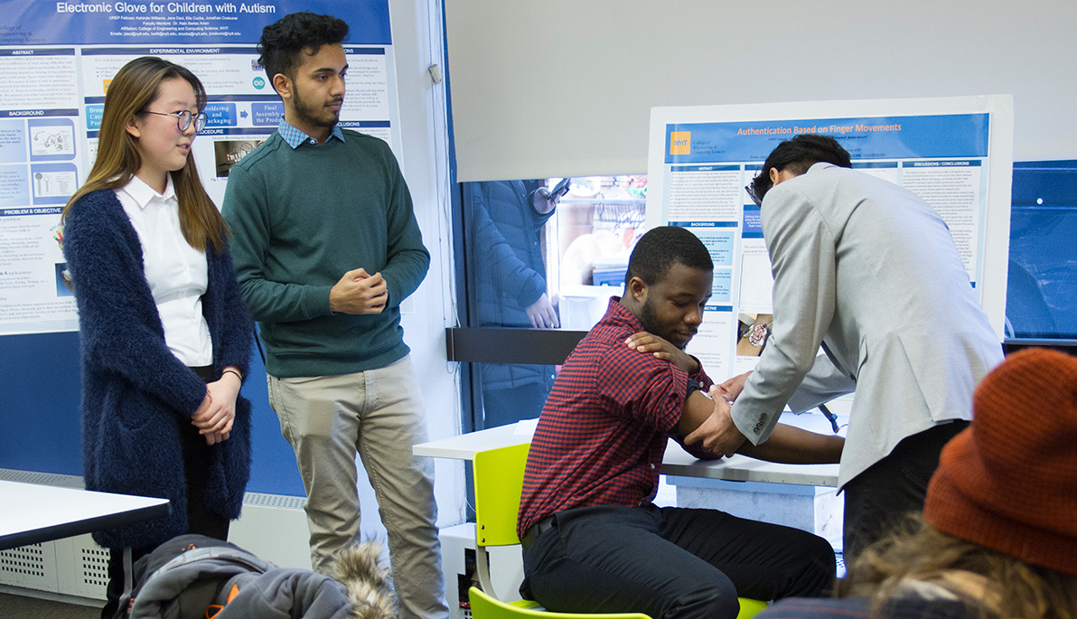 Two people look on and as one researcher seems to be performing a procedure on another. 