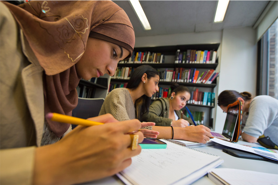 Students studying in a library at table. 