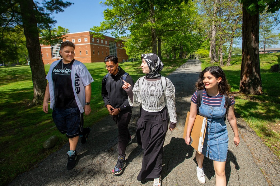 Four students walking a path on the New York Tech Long Island campus.