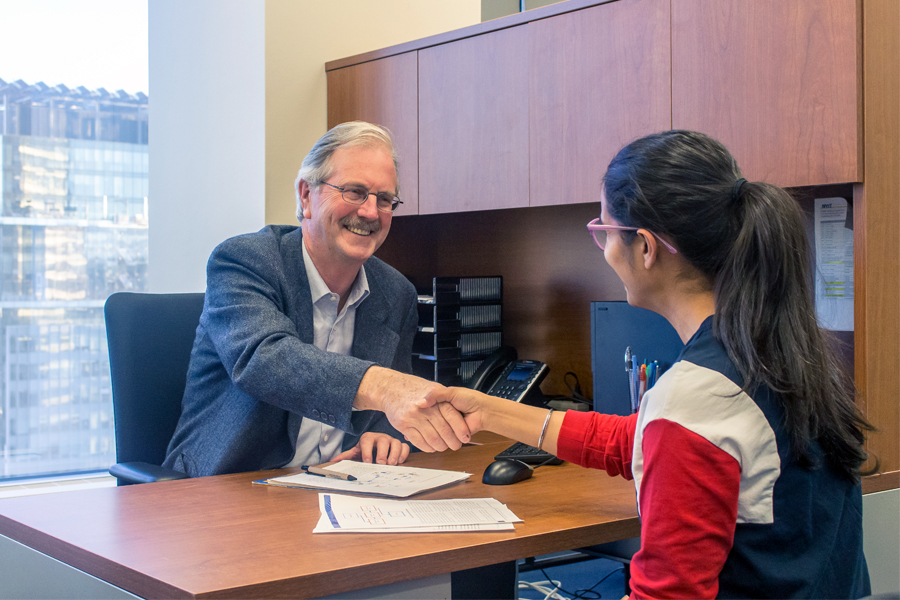 A student advisor shaking hands with a student. 