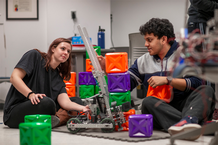 Two College of Engineering and Computing Sciences students at New York Tech, one male and one female, build a model structure with sheet metal and plastic blocks.