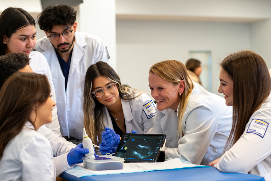 An instructor shows three New York Tech School of Health Professions students how to use ultrasound equipment, with results displayed on a tablet.