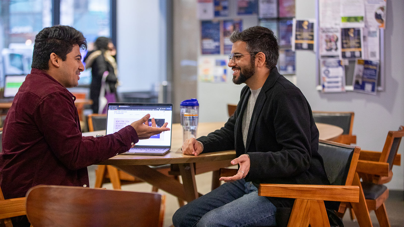 Two graduate students converse in a New York Tech lounge.