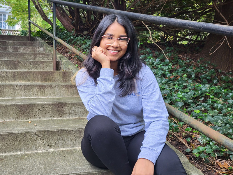 Sitting outdoors on a set of steps, Yamini Bhaveshbhai Patel smiles while talking about her time at New York Tech.