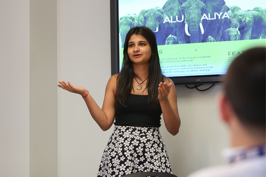 A student presenting in front of a screen. 