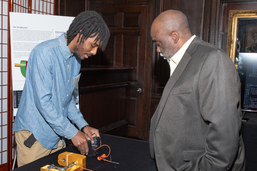 A student demonstrating his project at a poster board presentation. 