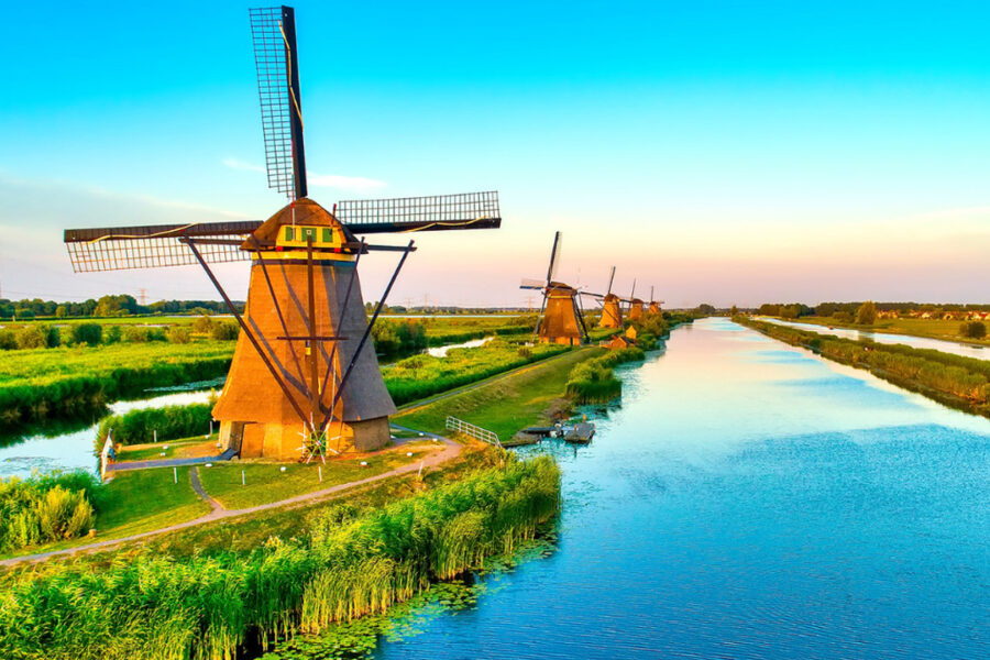 Line of windmills by a river bank.