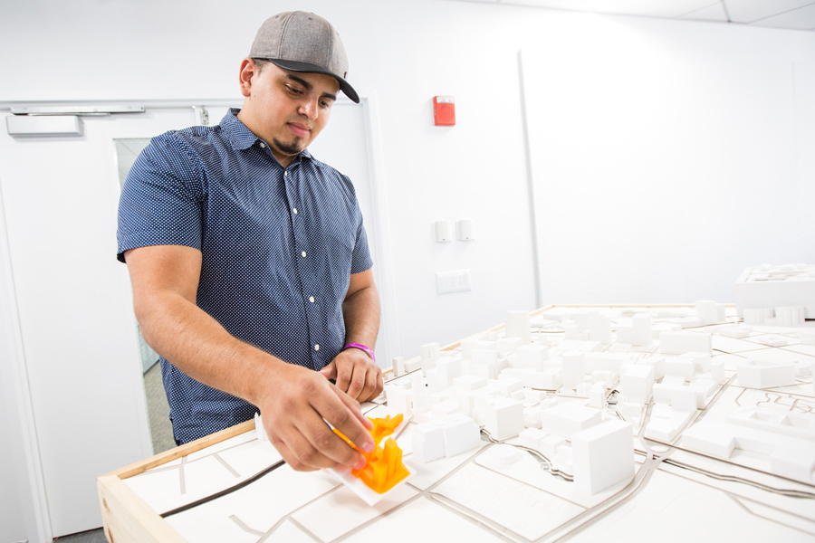 An architecture student working on a model of a city. 