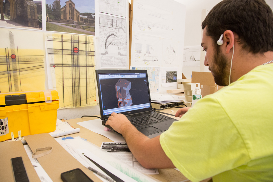 A student working on a laptop in a design workshop.