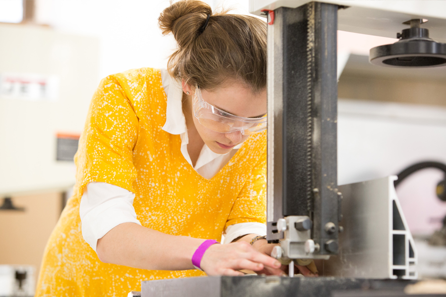 A student working on a machine to construct a model. 