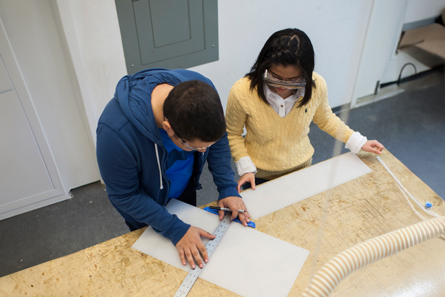 Two students working on a table in a design workshop.