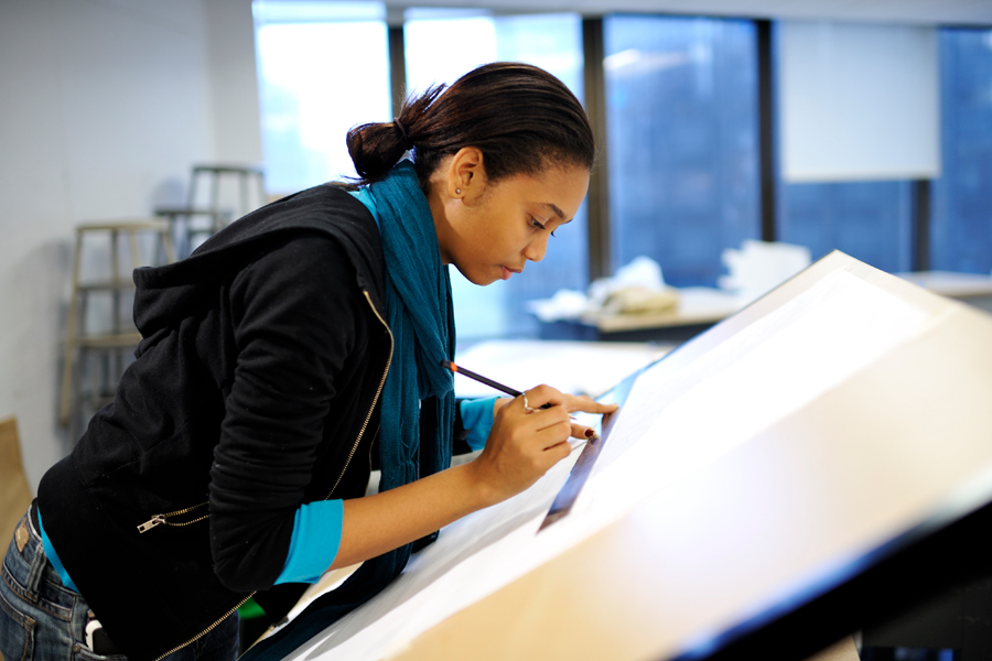 An architecture student sketches at a table.