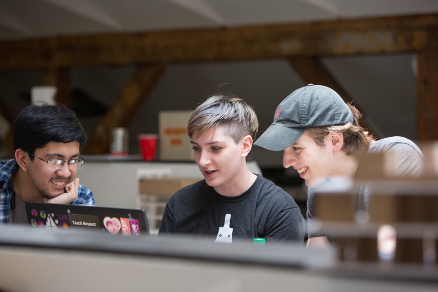 Three students working in a lab with a laptop.