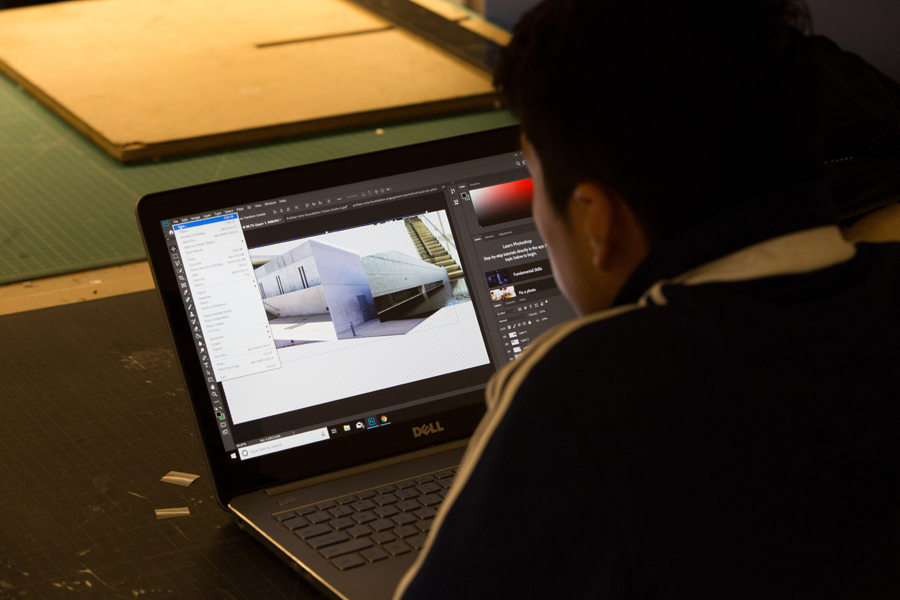 A student working on a laptop with digital model of a building.