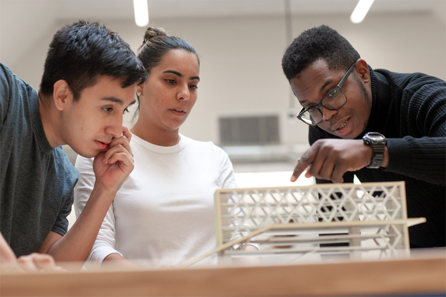 Three students working on a model in a fabrication lab.