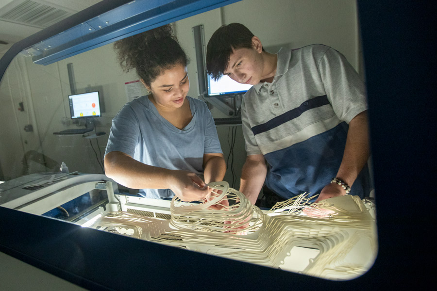 Two student working with a model in a fabrication lab.