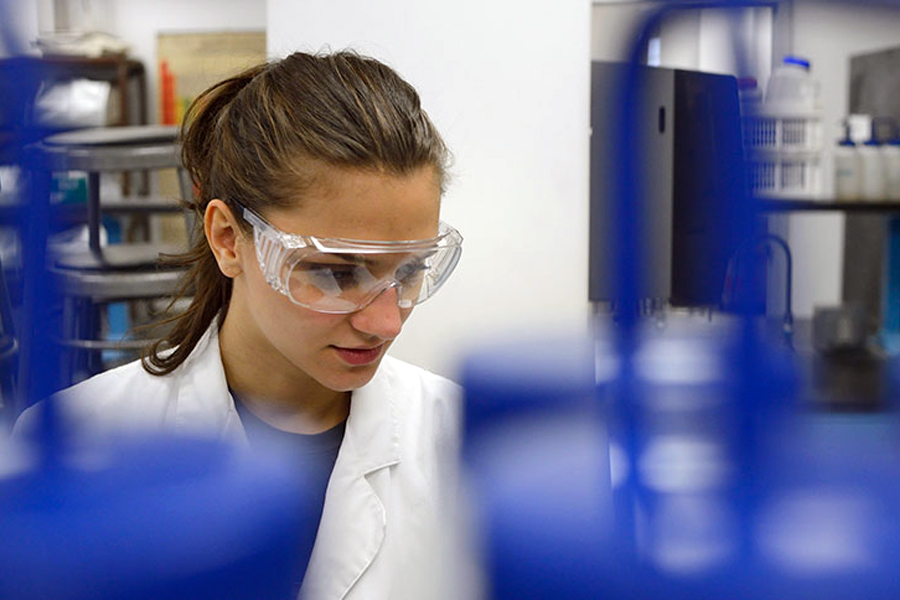 A student with goggles works in a lab in the College of Arts and Sciences.