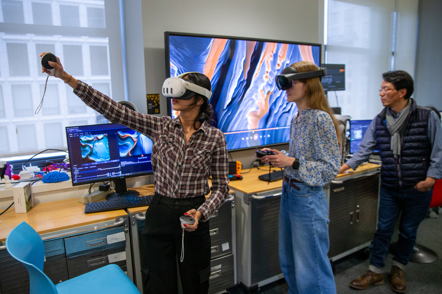 A professor and two students wearing headsets experiment with the instructional possibilities of virtual reality technology.