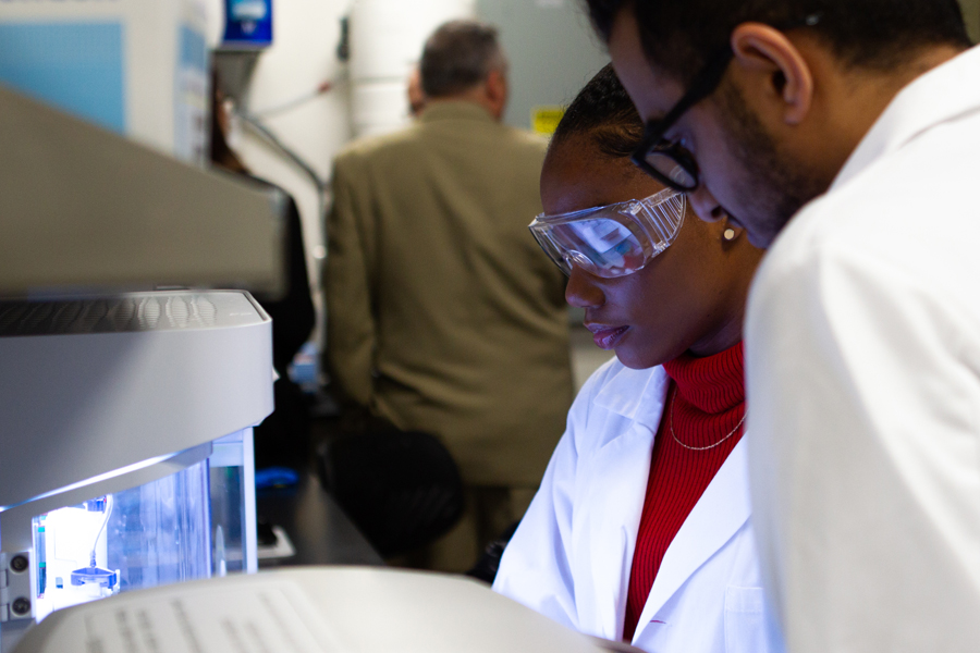 Two people in white lab coats working in a lab. 