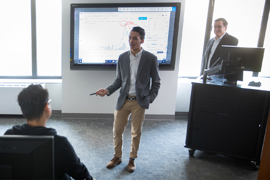 A student presenting on a SMART board in front of the class. 