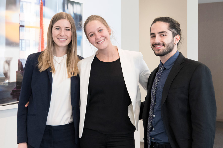 Three people in business attire pose for a photo.