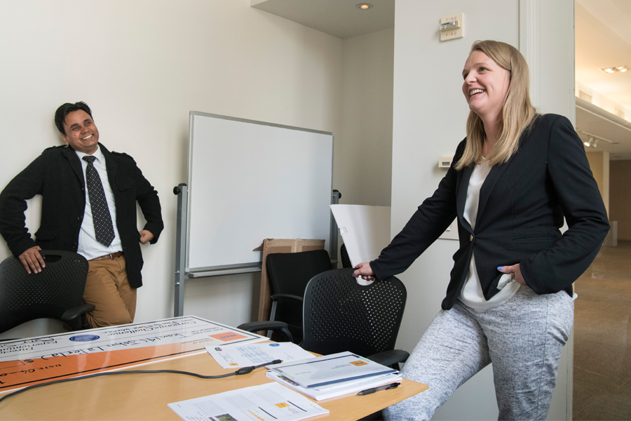 Two people in a conference room with a large table and a white board in the background. 