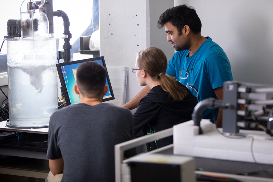 Three student working front of a computer in lab. 