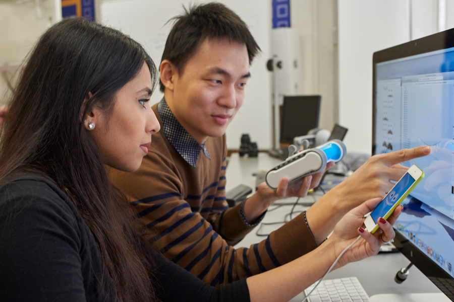 Two students in a lab sitting in front of a computer. 