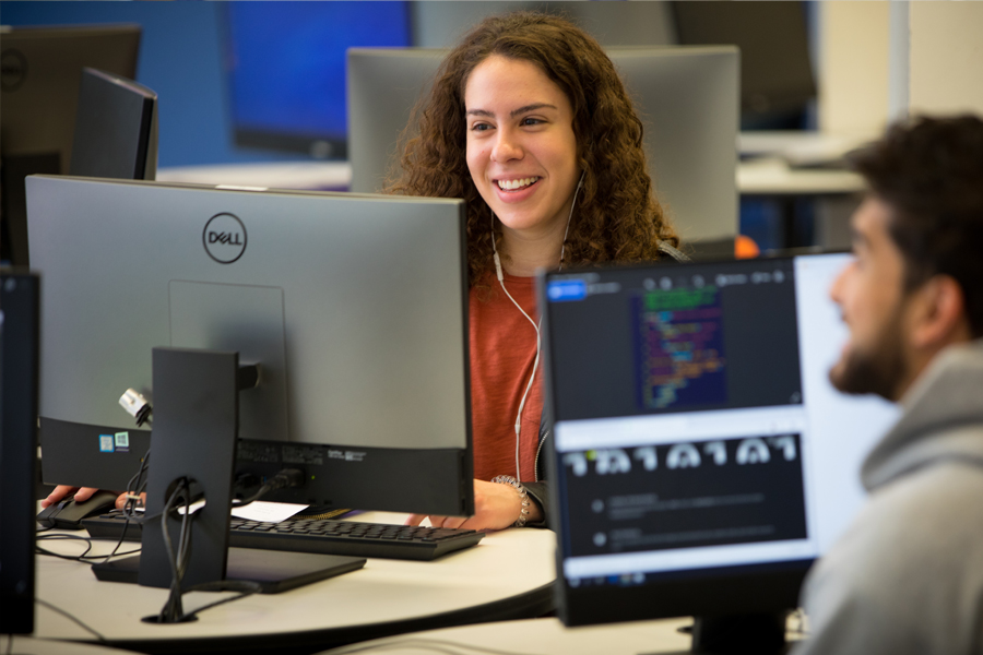 Two students sitting across from each other in a computer lab.