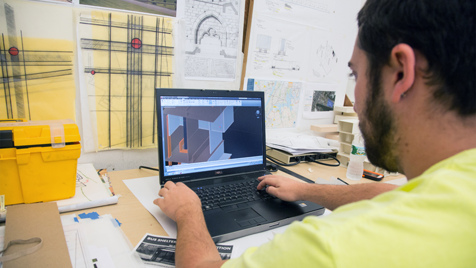 A student works on an architectural rendering at a computer in a classroom