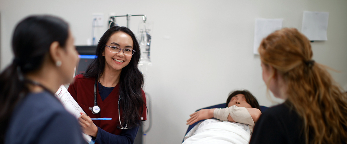 Three nursing students practice treatment in the simulation center.