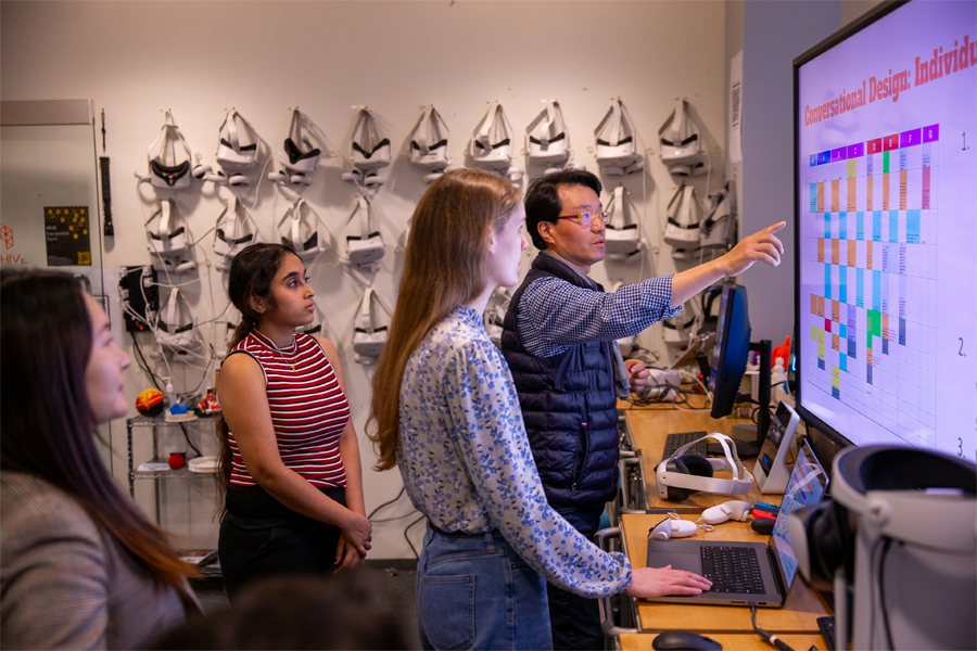 A faculty member works with students in The HIVE (Home for Innovation, Visualization, and Exploration).