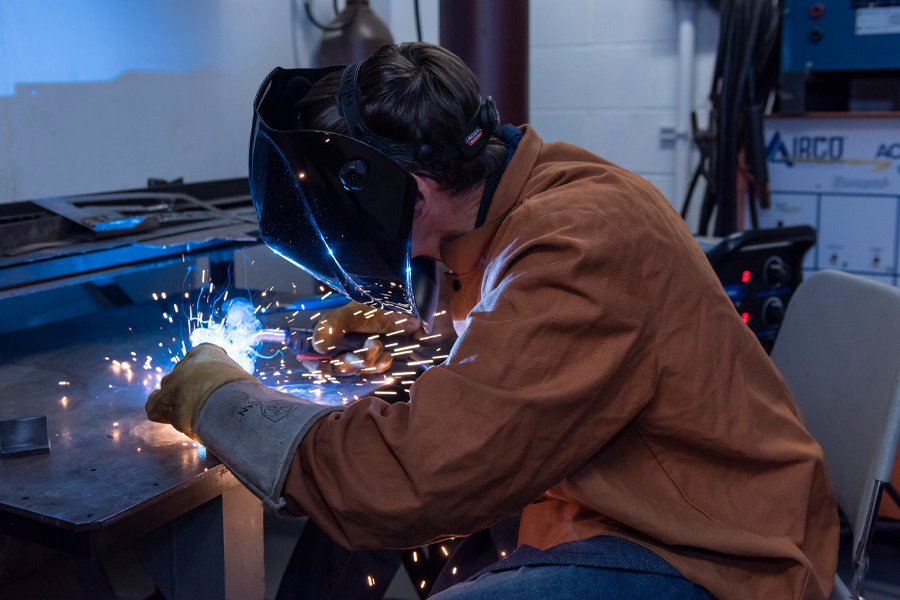 A person wearing projective equipment using a welder. 