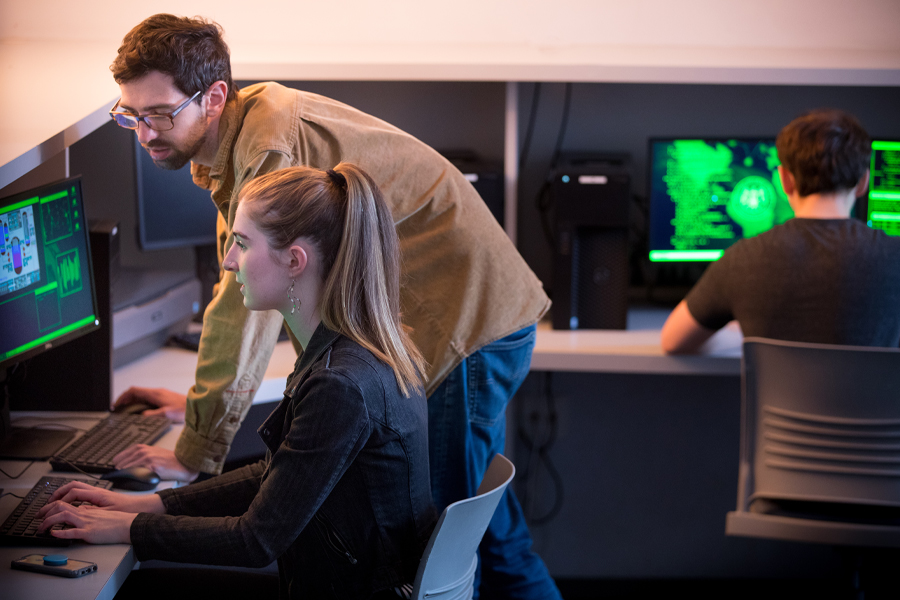 Three College of Engineering and Computing Sciences students use programs in a computer lab.