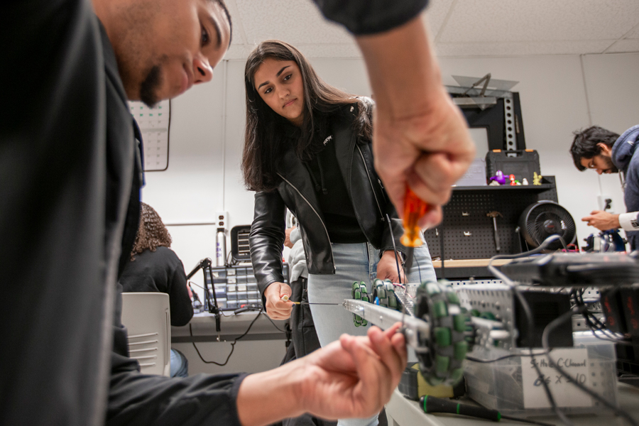 Two electrical and computer engineering technology students at New York Tech, one male and one female, put the finishing touches on a robot they are building.