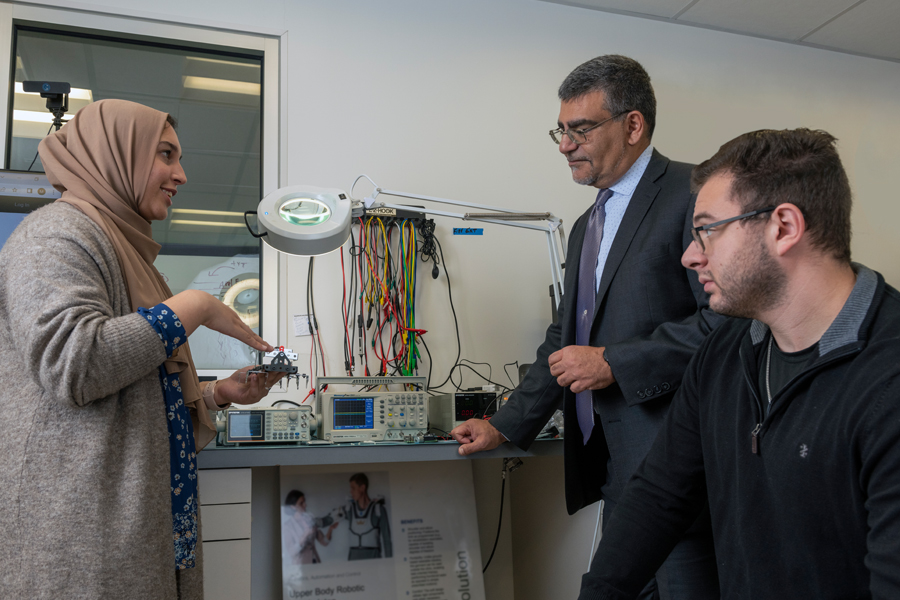 A female student discusses her upper body robotics project with the dean and a male student at New York Tech's Entrepreneurship and Technology Innovation Center.