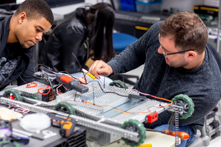 Two students in a lab working on an engineering project. 