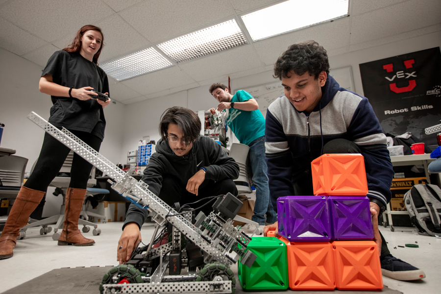 4 students in a lab working on a mechanical engineering project.