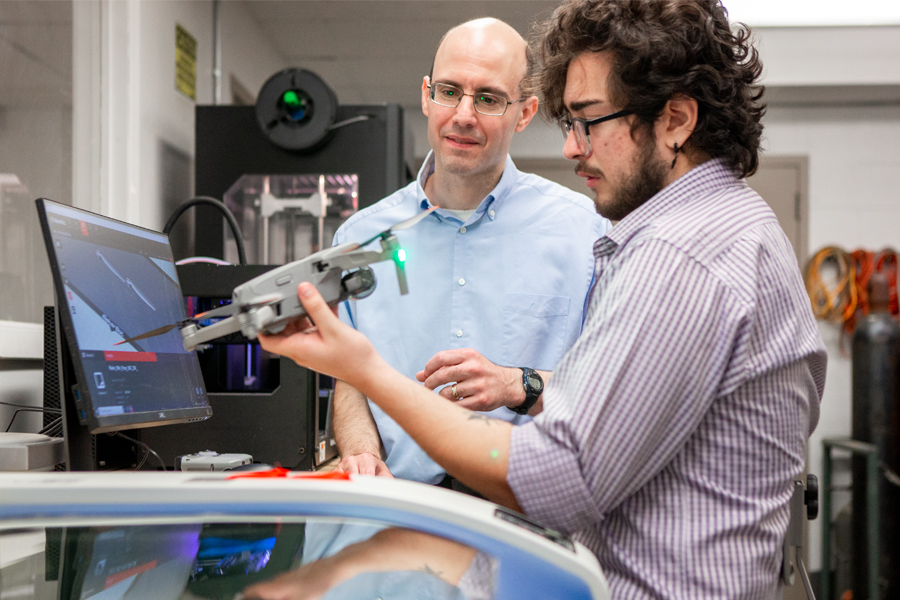 Two researchers working on a drone in a lab. 