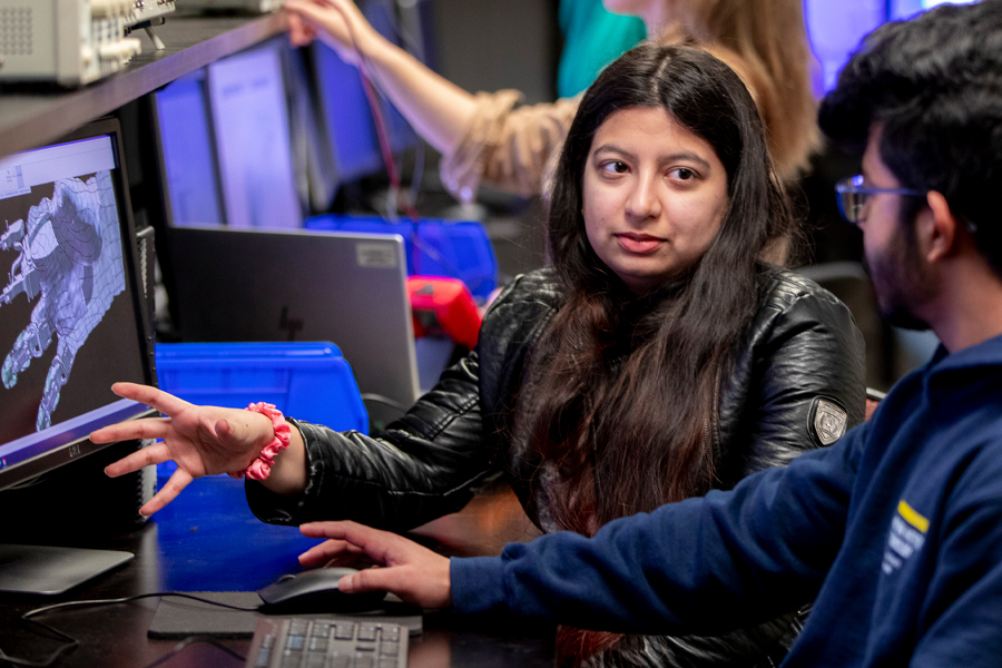 Two students in a computer lab for the College of Engineering and Computing Sciences at New York Tech discuss a 3-D CAD drawing of a hand.