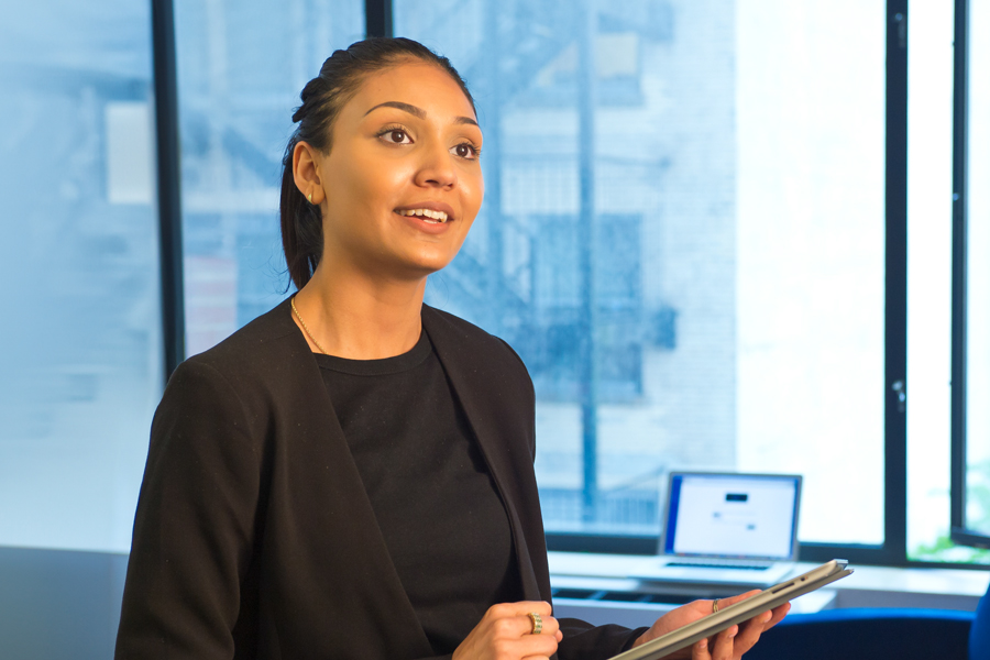 A person wearing business attire in a professional office holding a tablet. 