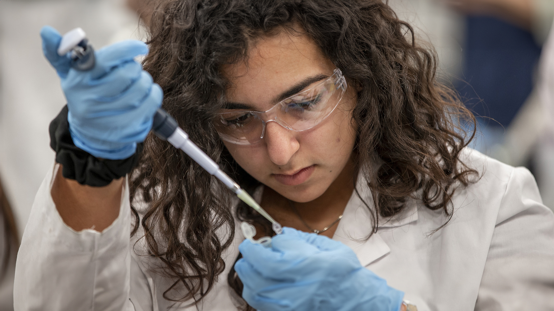 A student works with a pipette and a vial.