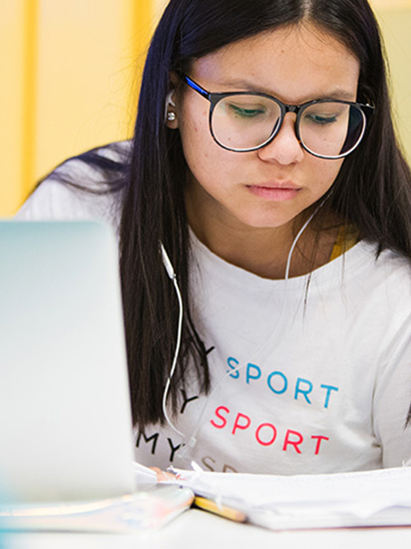 A student completes online assignments on her laptop with headphones.