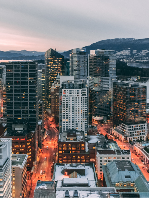 The city of Vancouver shown as dusk with lights and traffic movement.